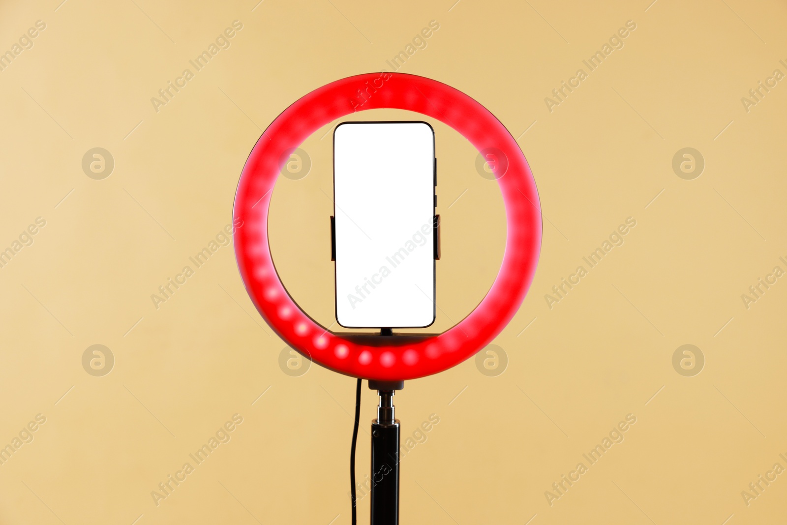 Photo of Ring lamp with smartphone on beige background