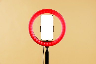 Photo of Ring lamp with smartphone on beige background