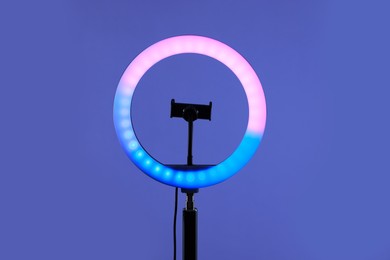 Photo of Ring lamp with holder for smartphone against purple background