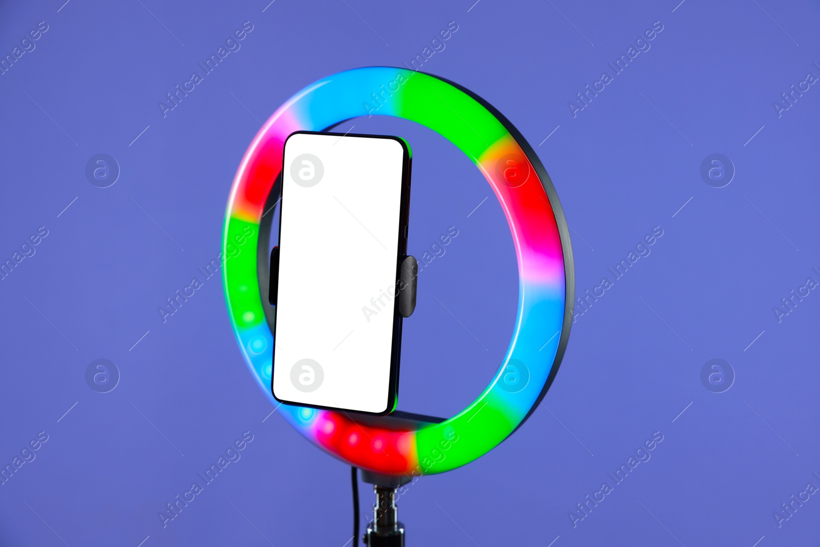 Photo of Ring lamp with smartphone on purple background