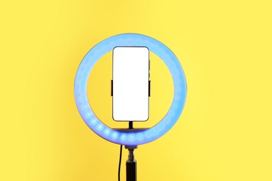 Photo of Ring lamp with smartphone on orange background