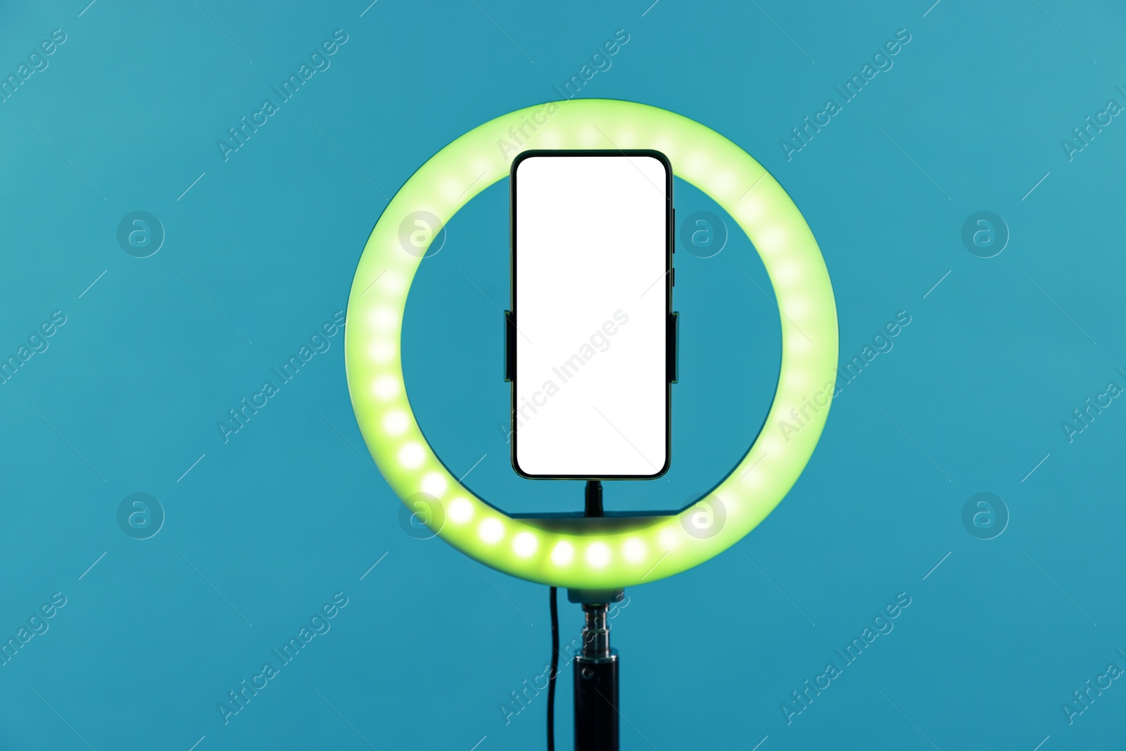 Photo of Ring lamp with smartphone on light blue background