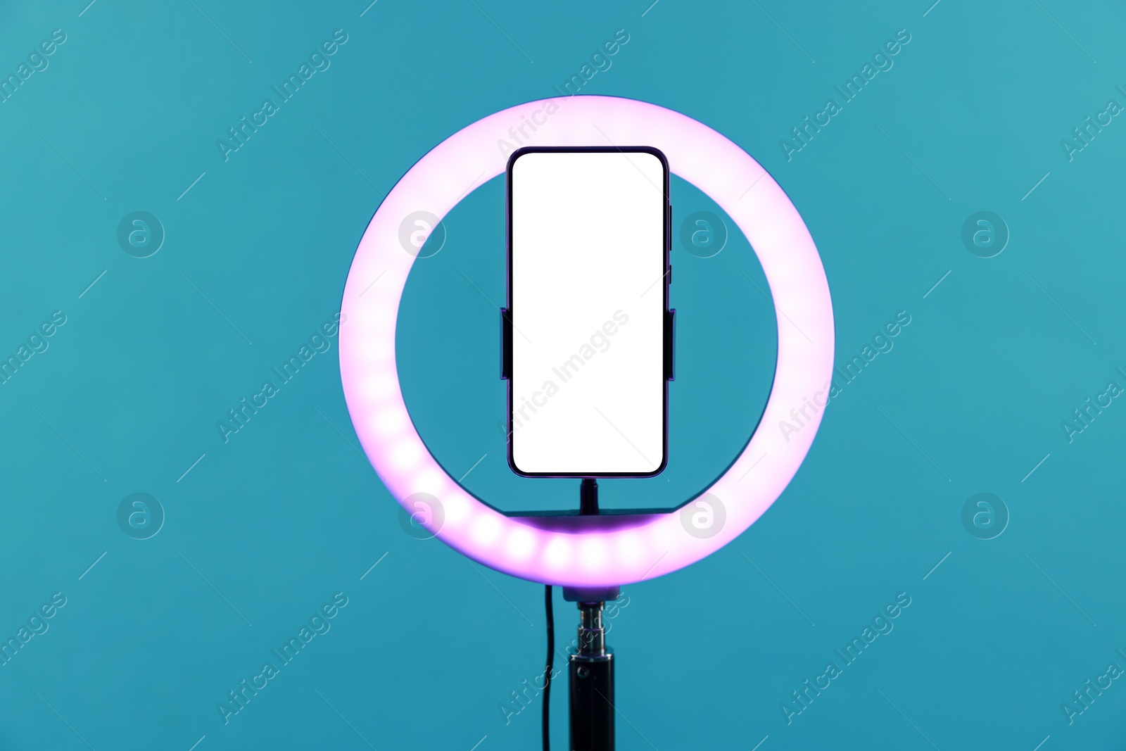 Photo of Ring lamp with smartphone on light blue background