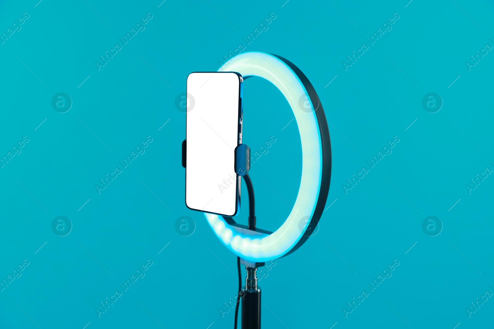 Photo of Ring lamp with smartphone on light blue background