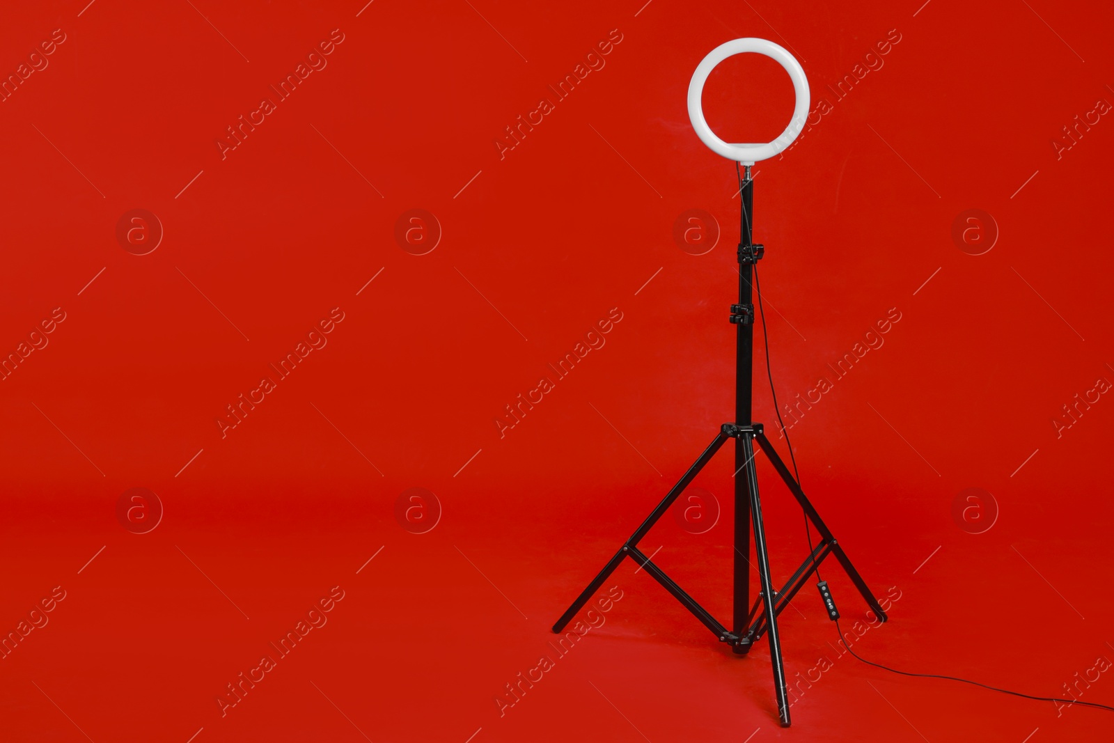 Photo of Ring lamp on stand against red background, space for text