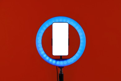 Photo of Ring lamp with smartphone on red background