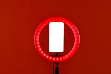 Photo of Ring lamp with smartphone on red background