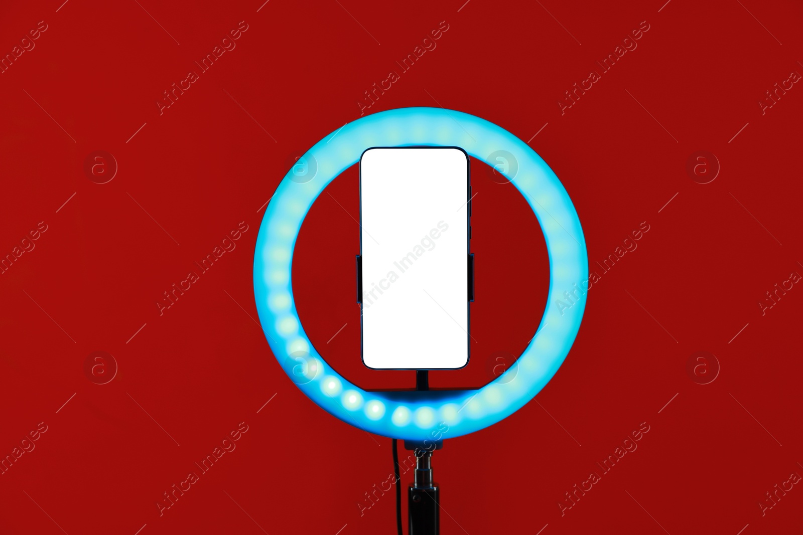 Photo of Ring lamp with smartphone on red background