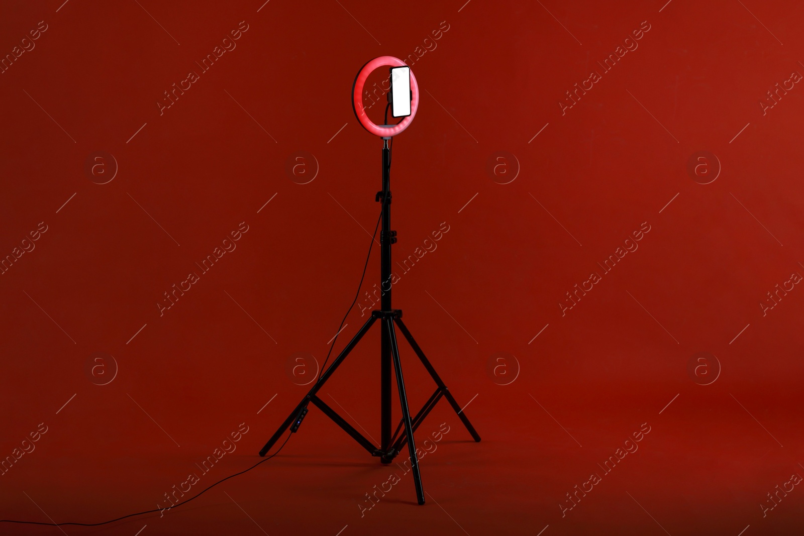 Photo of Ring lamp with smartphone on red background