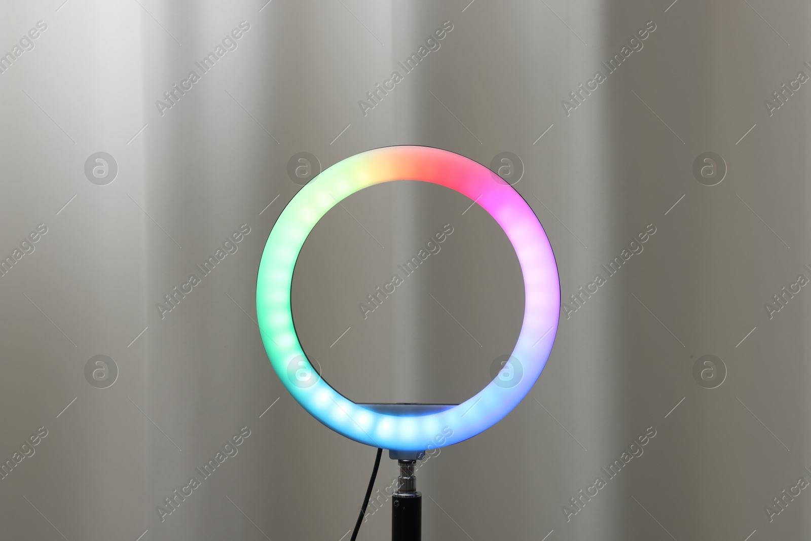 Photo of One glowing ring lamp near grey curtain