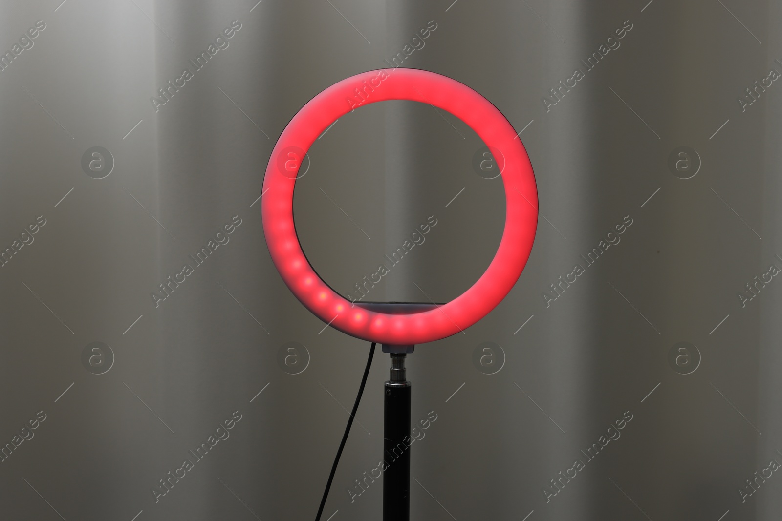 Photo of One glowing ring lamp near grey curtain