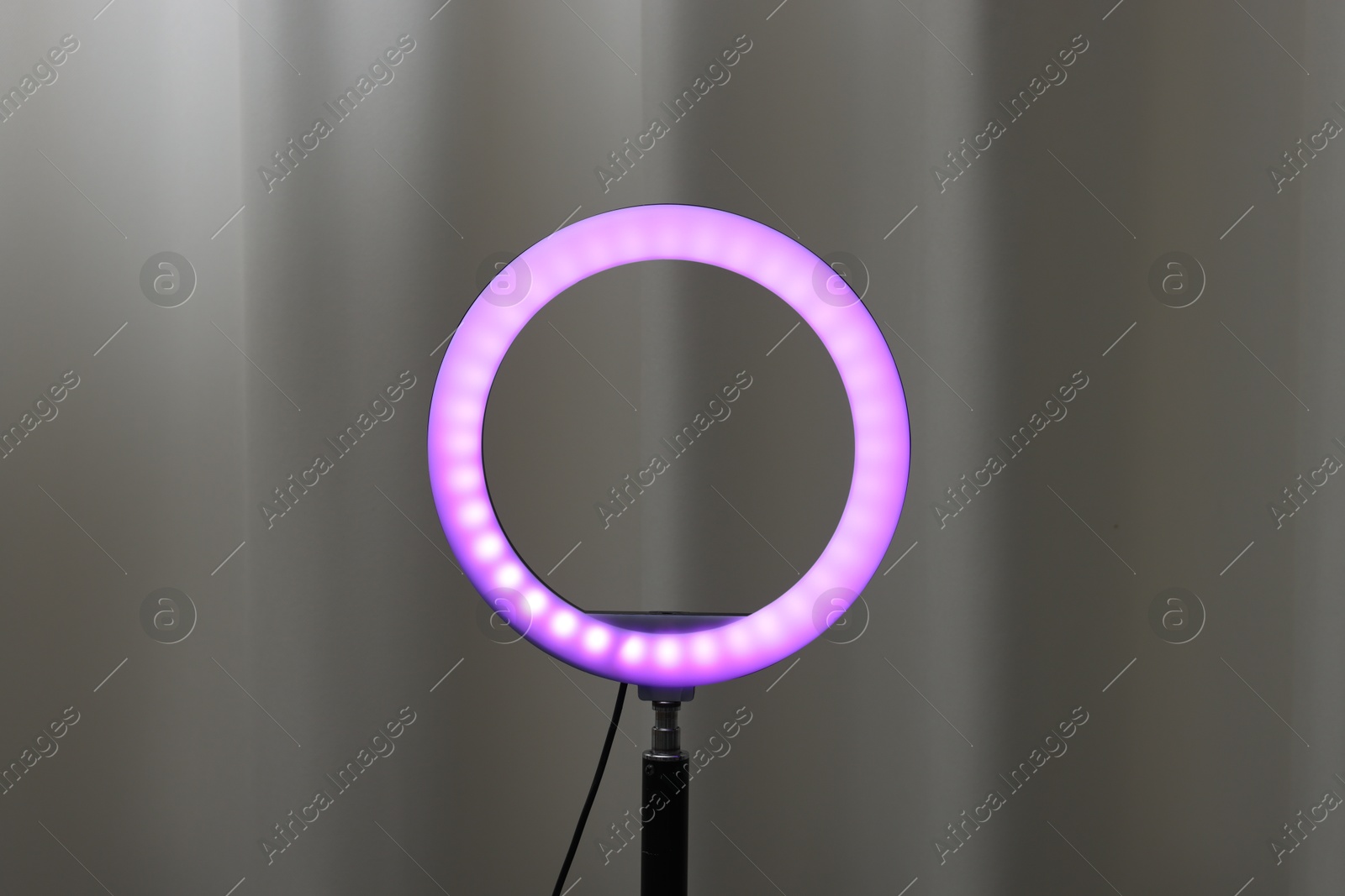 Photo of One glowing ring lamp near grey curtain