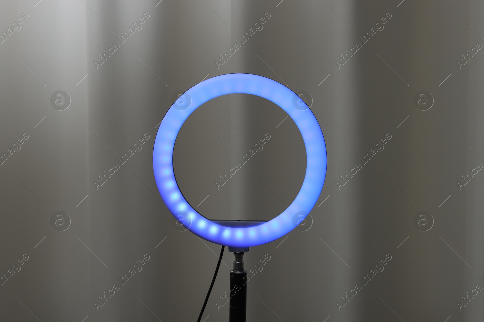 Photo of One glowing ring lamp near grey curtain