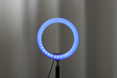 Photo of One glowing ring lamp near grey curtain