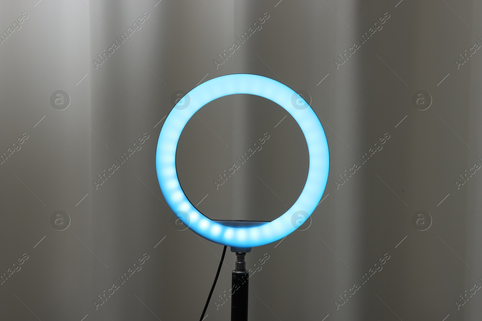 Photo of One glowing ring lamp near grey curtain