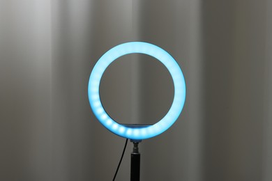 Photo of One glowing ring lamp near grey curtain