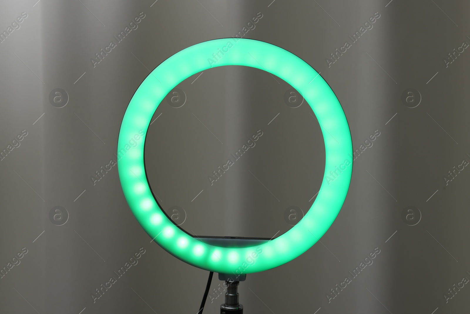 Photo of One glowing ring lamp near grey curtain