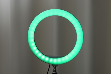 Photo of One glowing ring lamp near grey curtain