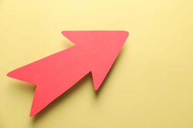 Photo of One red paper arrow on yellow background, top view. Space for text