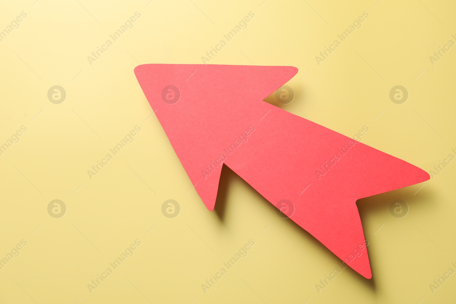 Photo of One red paper arrow on yellow background, top view. Space for text