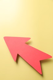 Photo of One red paper arrow on yellow background, top view