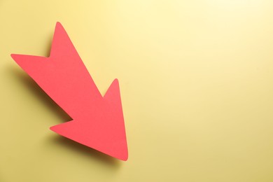 Photo of One red paper arrow on yellow background, top view. Space for text