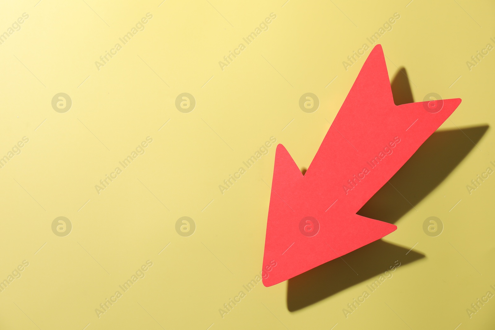 Photo of One red paper arrow on yellow background, top view. Space for text