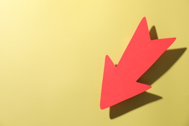 Photo of One red paper arrow on yellow background, top view. Space for text