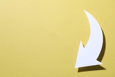 Photo of One white paper arrow on yellow background, top view. Space for text