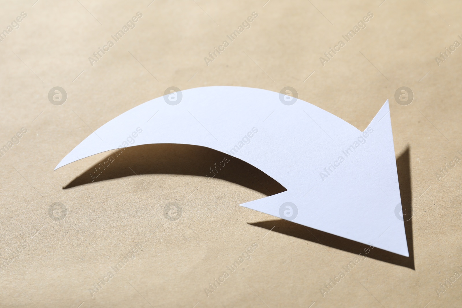 Photo of One white arrow on kraft background, closeup