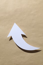 Photo of One white arrow on kraft background, top view