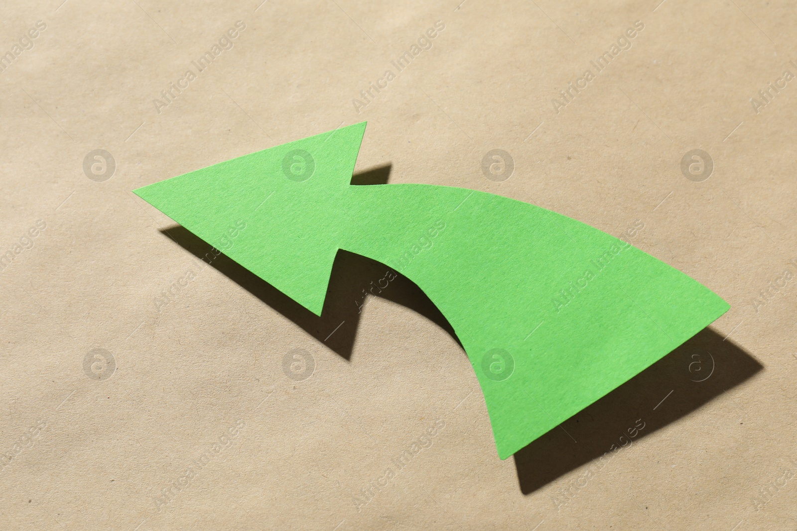 Photo of One green arrow on kraft background, closeup