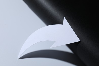 Photo of One white paper arrow on color background, closeup