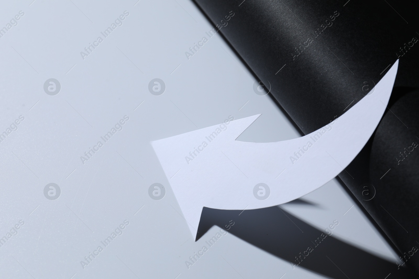 Photo of One white paper arrow on color background, closeup