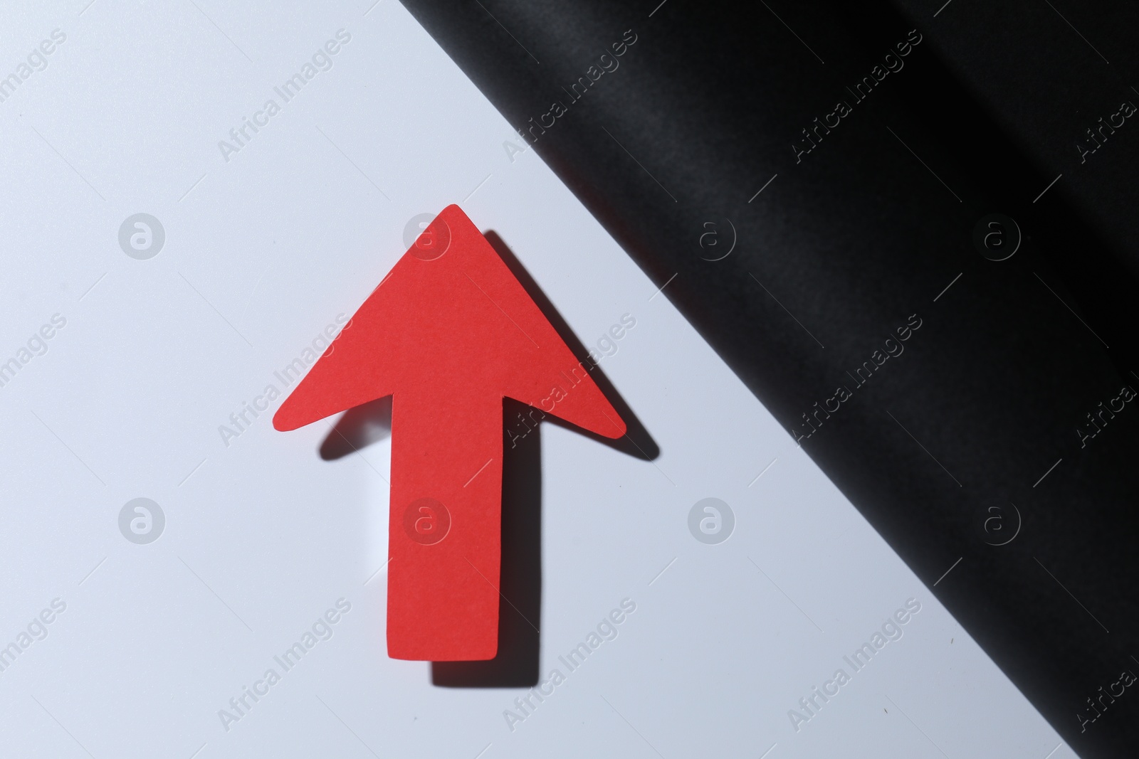 Photo of One red paper arrow on color background, top view