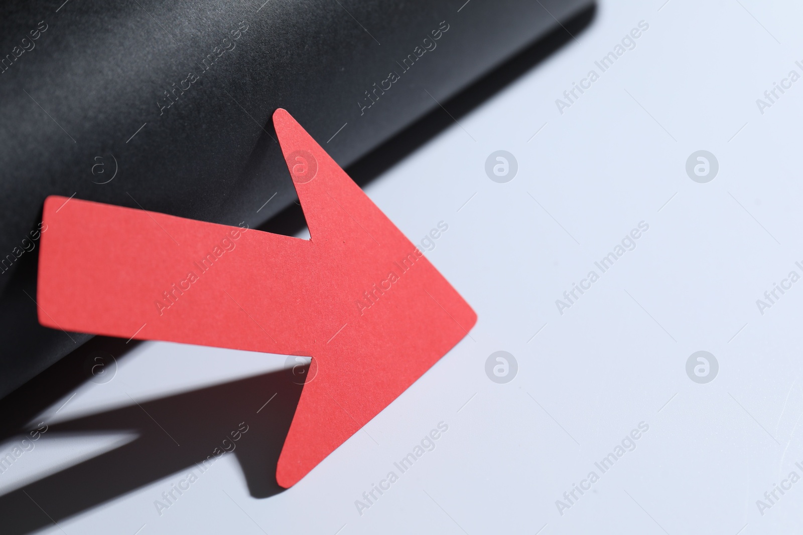 Photo of One red paper arrow on color background, closeup. Space for text