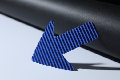 Photo of One blue paper arrow on color background, closeup