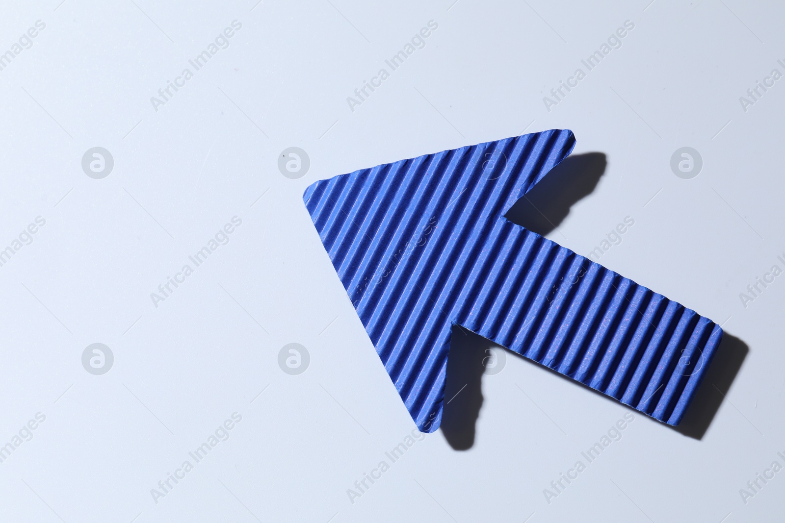 Photo of One blue paper arrow on white background, top view. Space for text