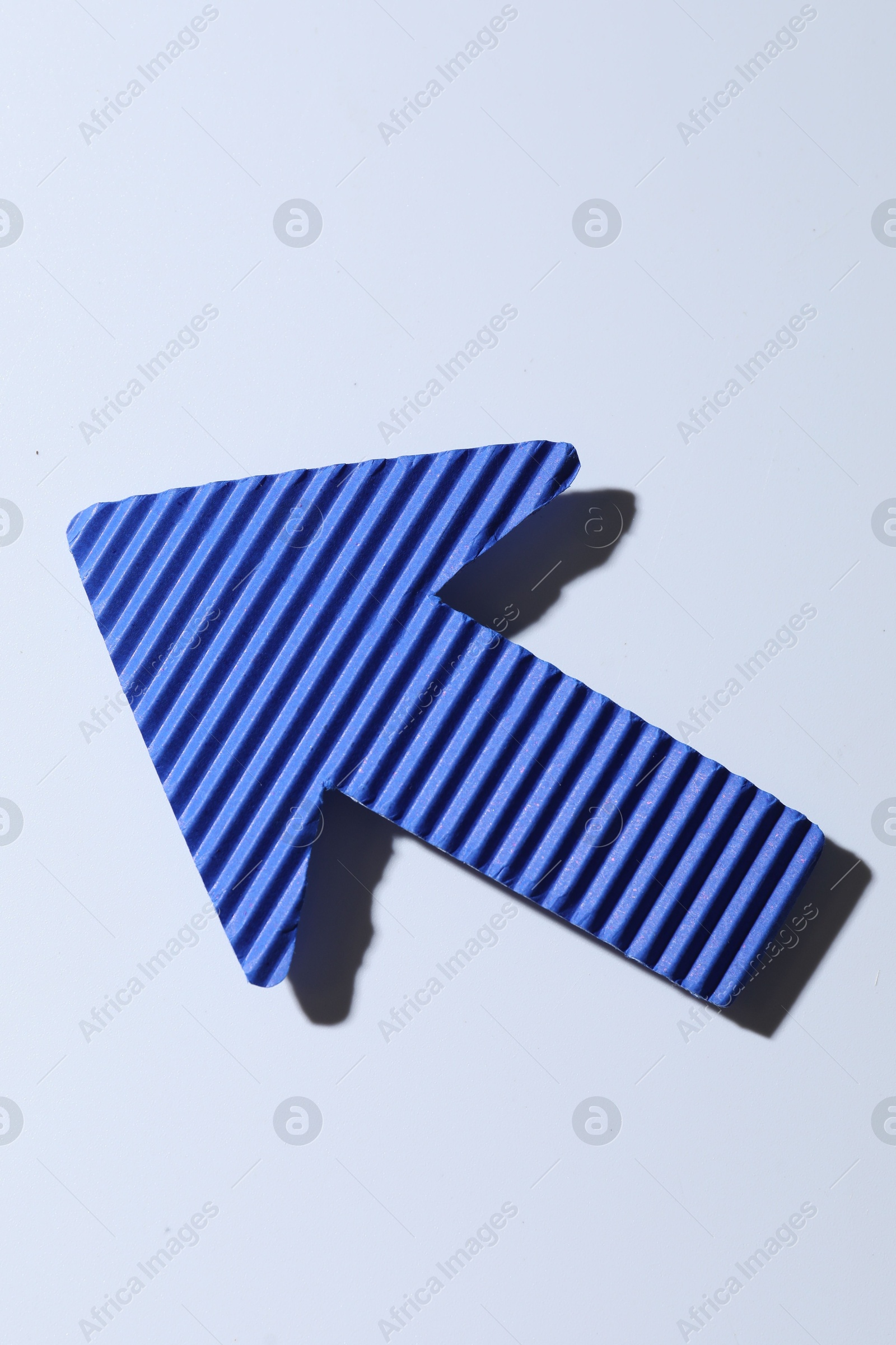 Photo of One blue paper arrow on white background, top view