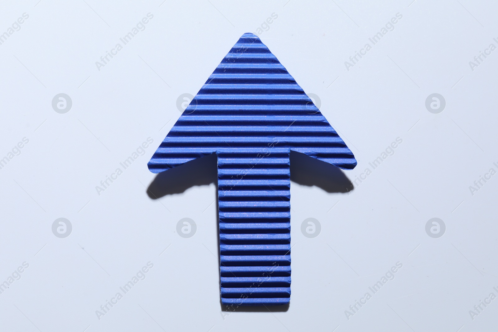 Photo of One blue paper arrow on white background, top view