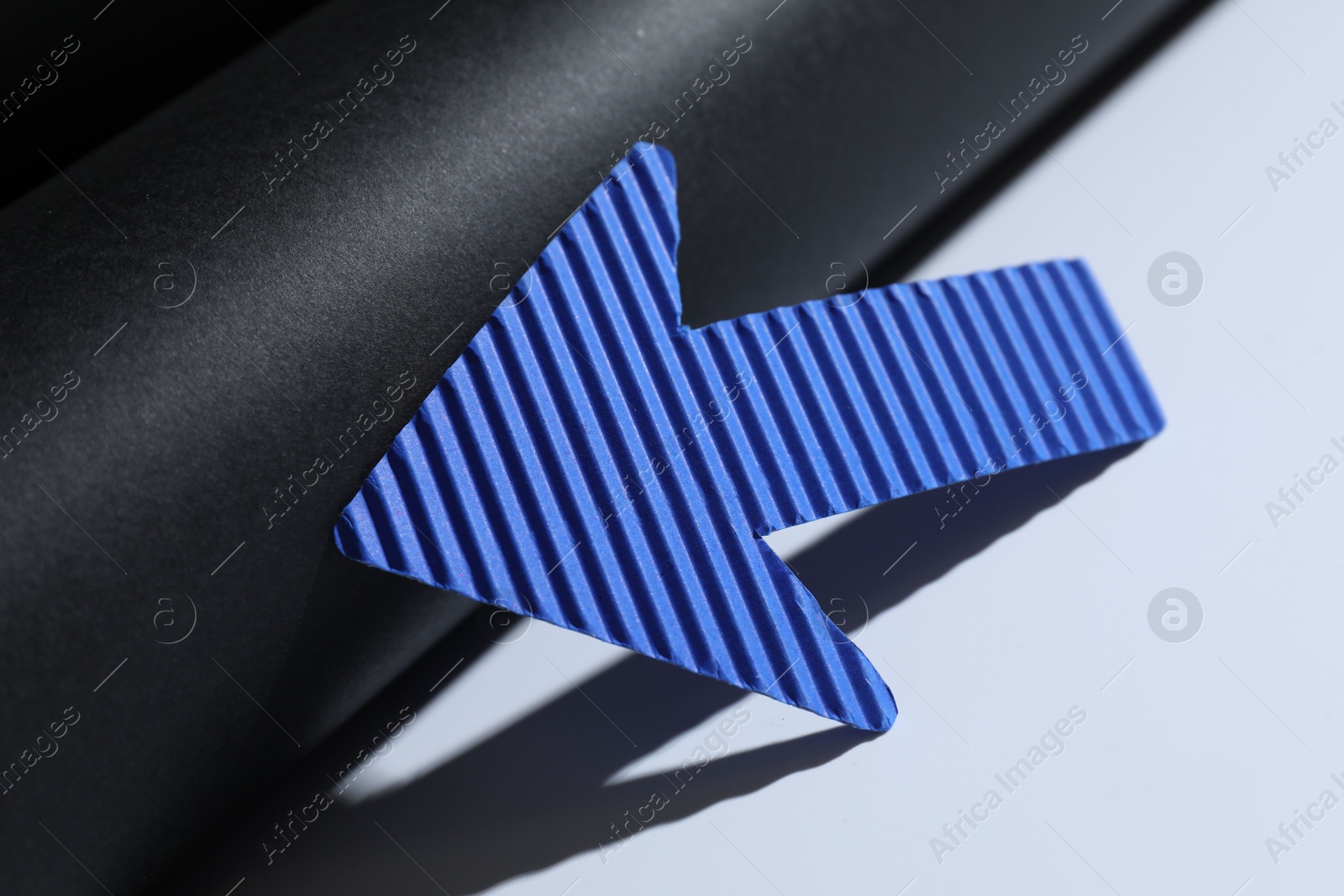 Photo of One blue paper arrow on color background, closeup