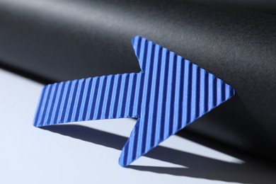 Photo of One blue paper arrow on color background, closeup