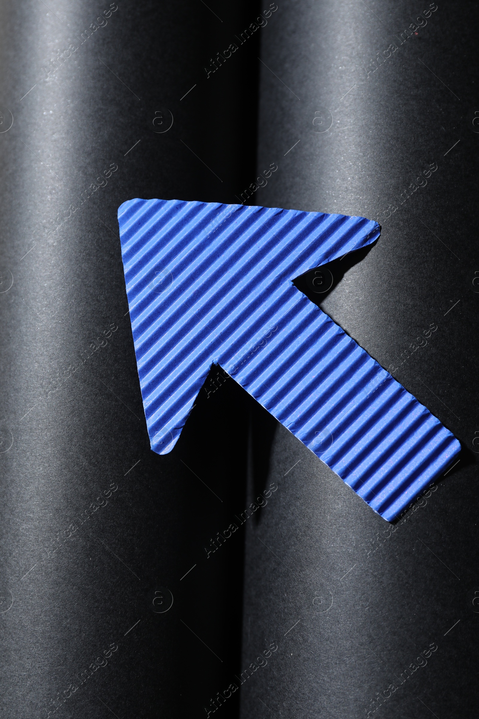 Photo of One blue paper arrow on black background, top view