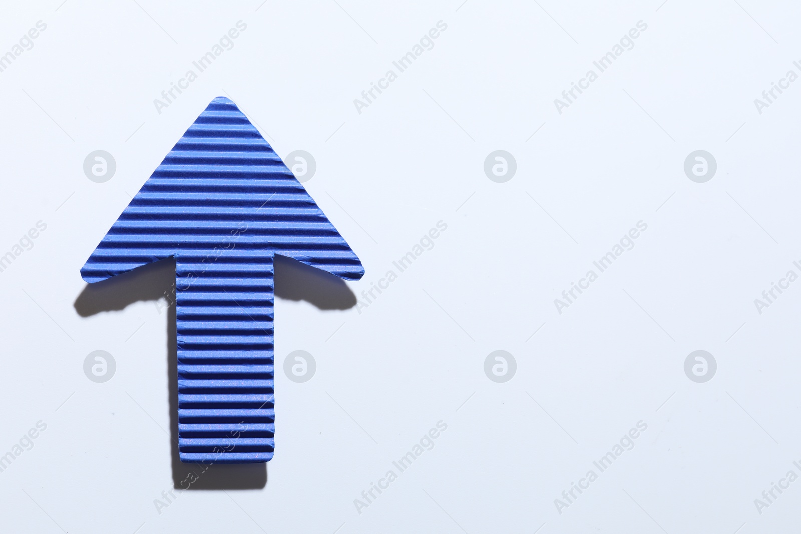 Photo of One blue paper arrow on white background, top view. Space for text