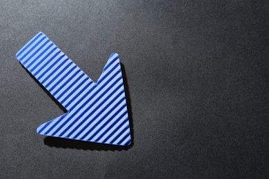 Photo of One blue paper arrow on black background, top view. Space for text