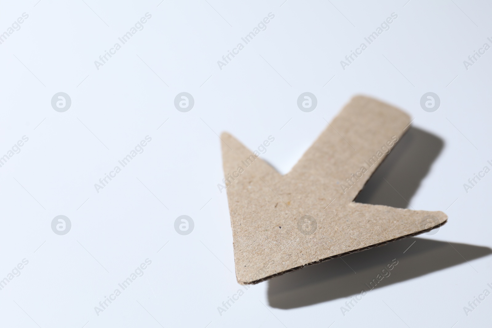 Photo of One kraft paper arrow on white background, closeup. Space for text