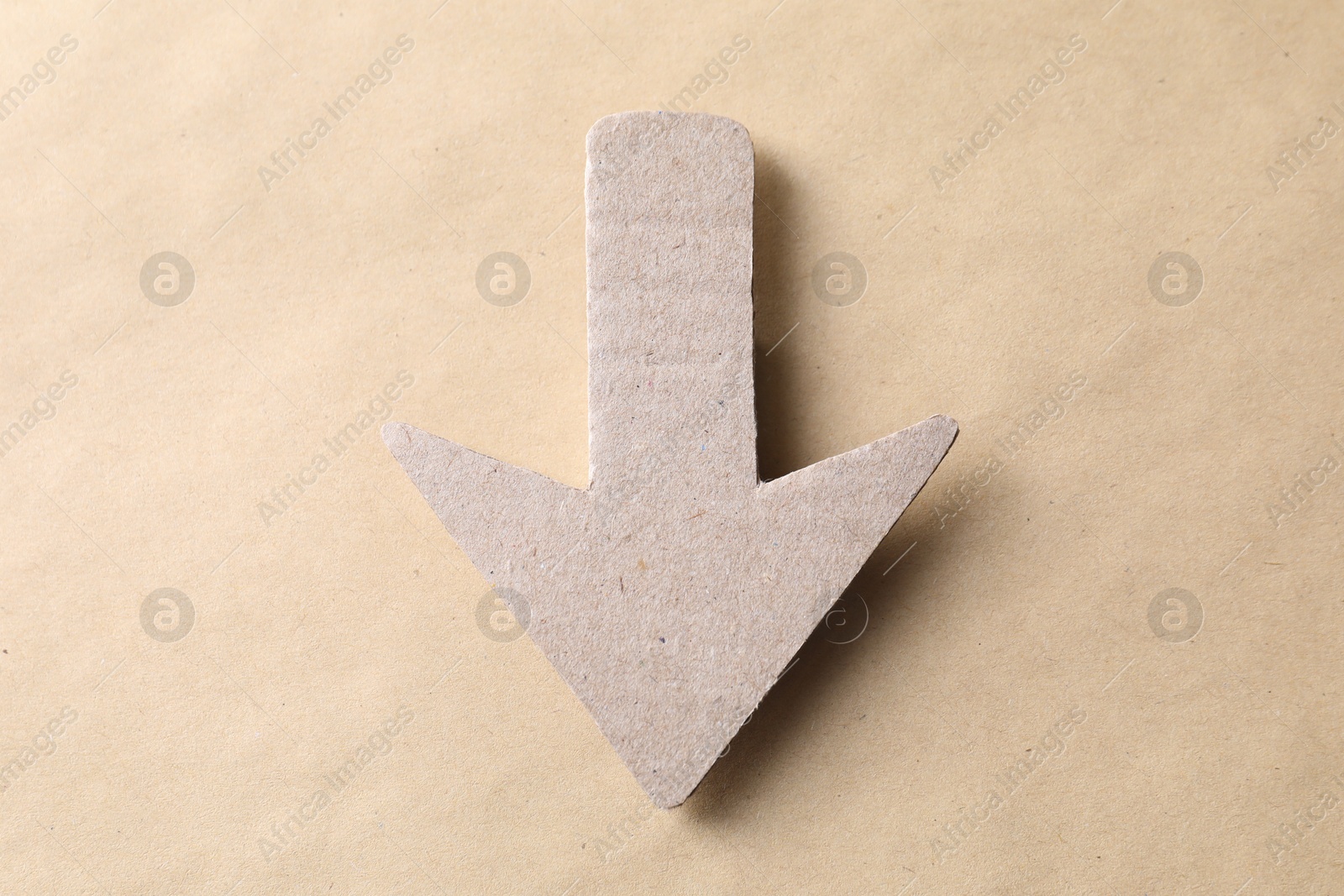 Photo of One paper arrow on kraft background, top view