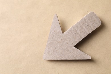 Photo of One paper arrow on kraft background, top view. Space for text