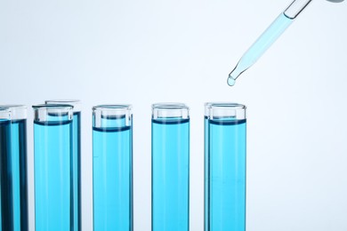 Photo of Dripping liquid into test tubes on white background