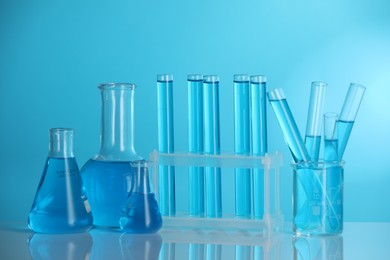 Photo of Laboratory glassware with liquid on mirror surface against blue background